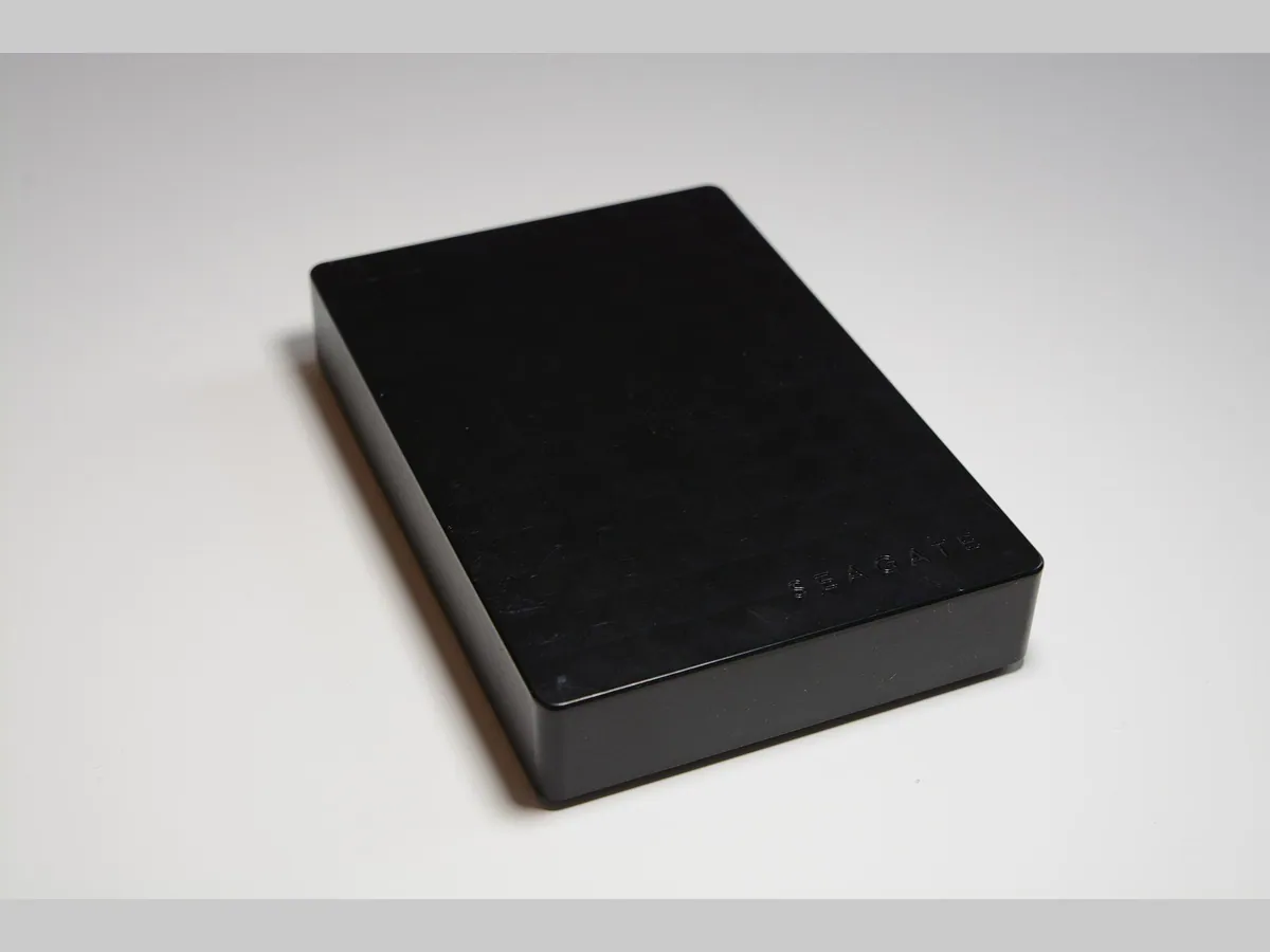 Disque dur externe portable noir posé sur fond blanc